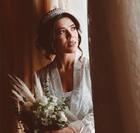 Bride in soft window light holding her bouquet
